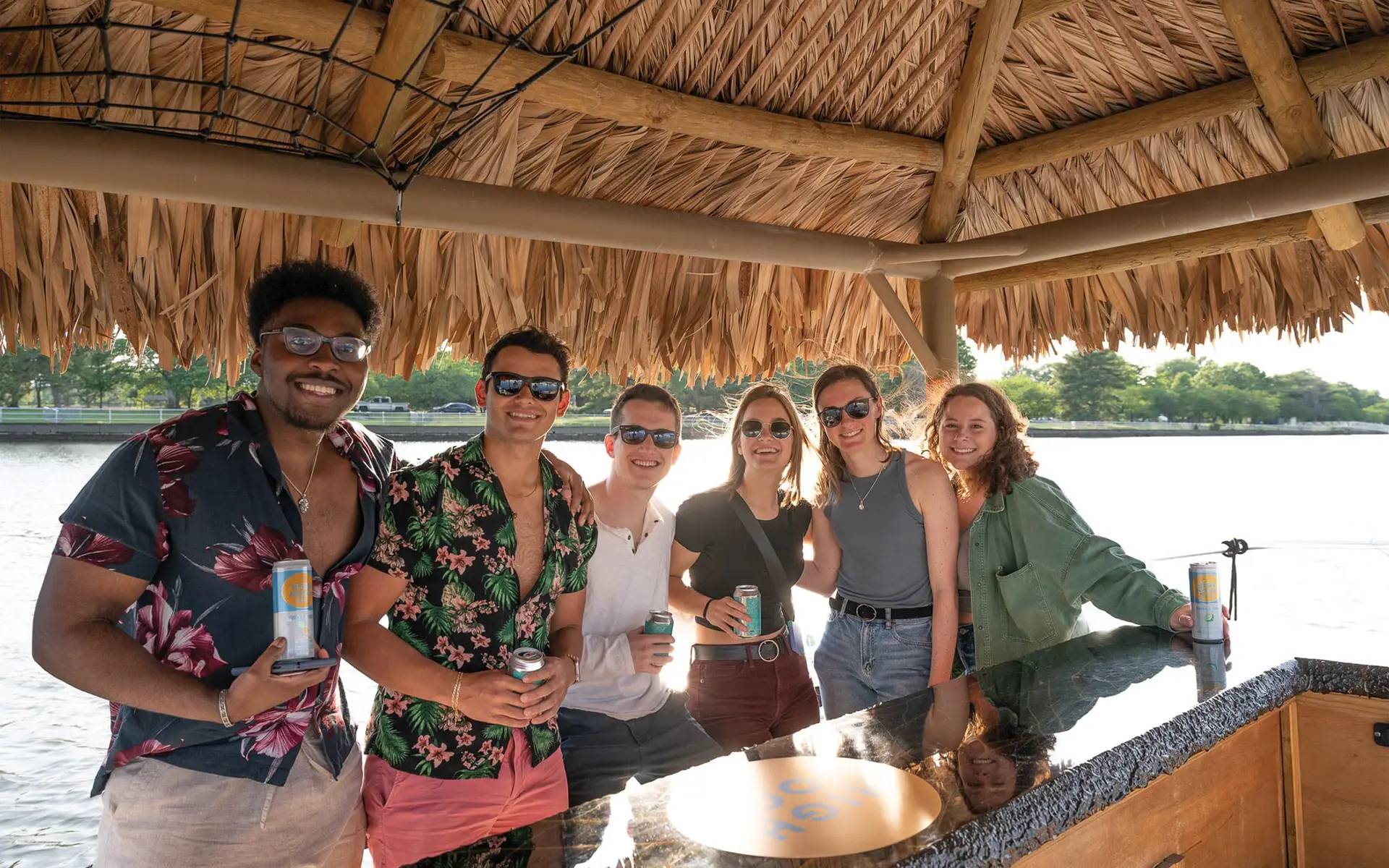 Tiki boat cruises out of Navy Yard near DC. Group photo of people with drinks on the water. Tikito - Potomac Tiki Club by Sea Suite Cruises.