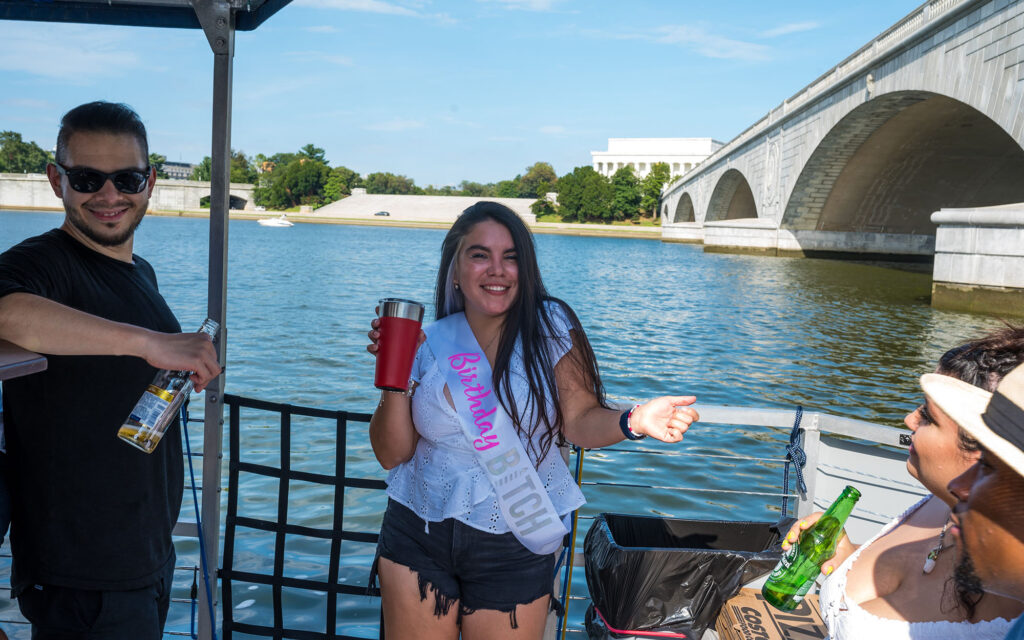 Woman dancing on a birthday party cruise on the Potomac River in Washington DC with the Arlington Memorial Bridge and Lincoln Memorial in the background.